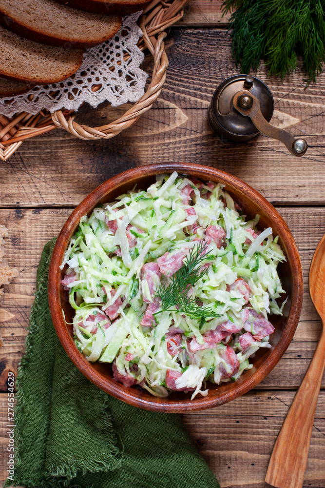 Salad with fresh cabbage and smoked sausage on a wooden table, top view, selective focus Salad with fresh cabbage and smoked sausage on a wooden table, top view, selective focus
