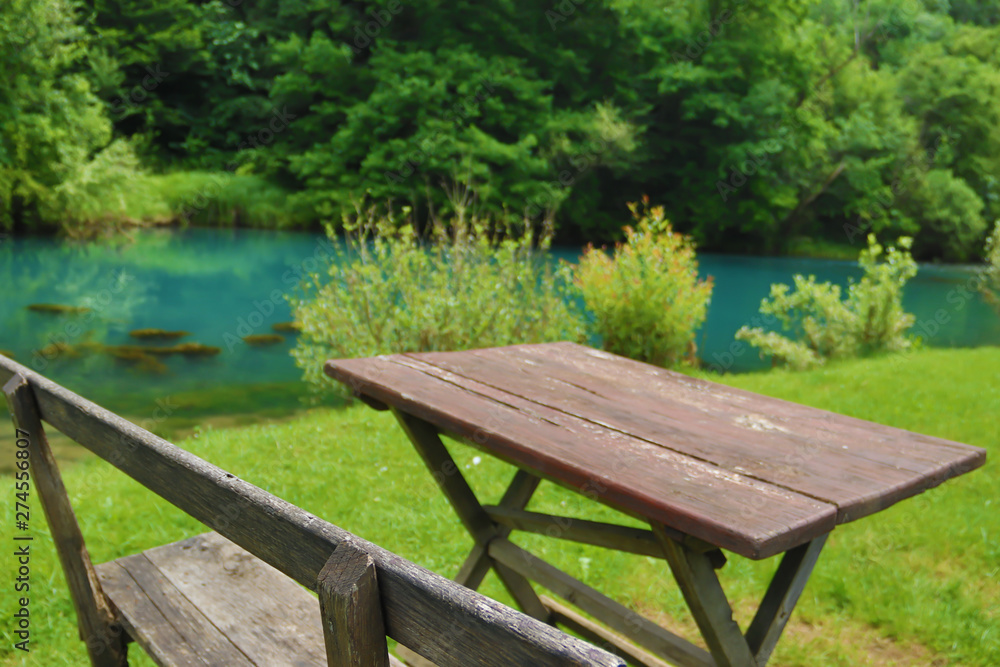 Home made wooden bench and table next to very scenic and green river bank Home made wooden bench and table next to very scenic and green river bank