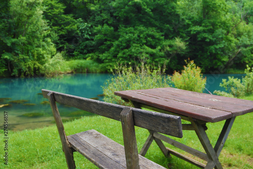 Home made wooden bench and table next to very scenic and green river bank