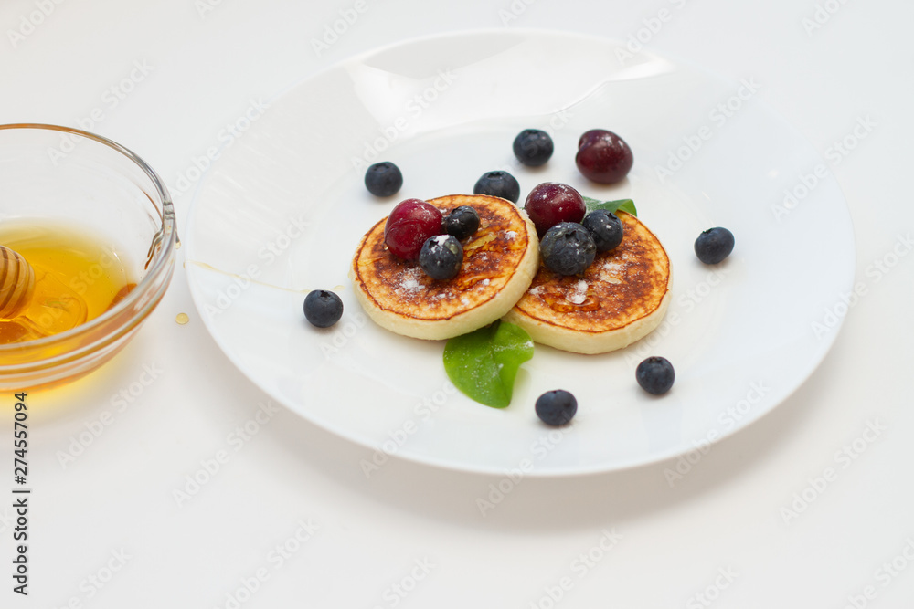 pancakes with blueberries on a white plate with a stick for honey pancakes with blueberries on a white plate with a stick for honey
