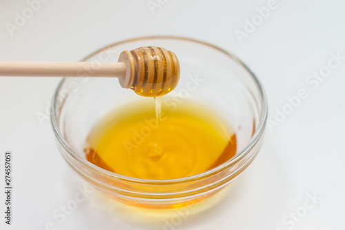honey dripping from dipper on white background