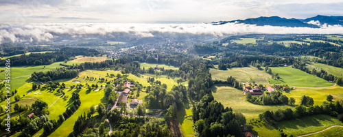 Fototapeta Naklejka Na Ścianę i Meble -  Aerial Bad Toelz Bavarian Alps. Golf Course. Blomberg Mountain. Morning Drone Shot with some clouds in the sky