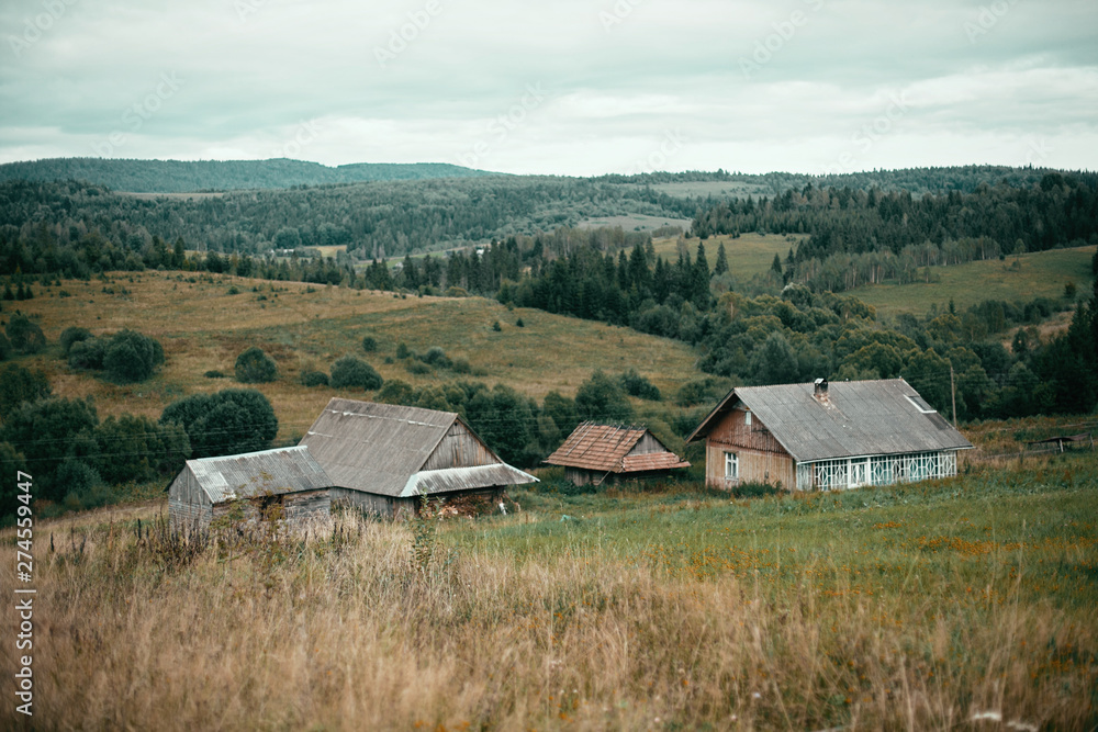 Beautiful old wooden houses on hills and sunny meadow in mountains. Rural simple life in countryside, . Atmospheric image. Mountain scenery