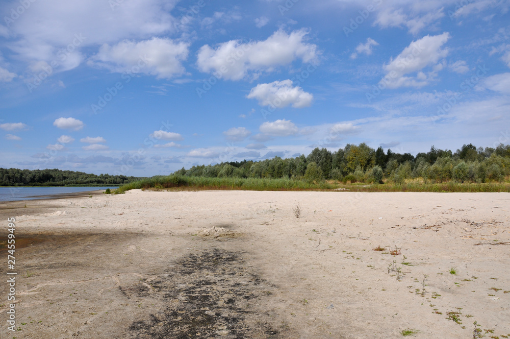 Wide blue river is slow flowing. Summer. Sunny weather and white sand. green trees far away Wide blue river is slow flowing. Summer. Sunny weather and white sand. green trees far away
