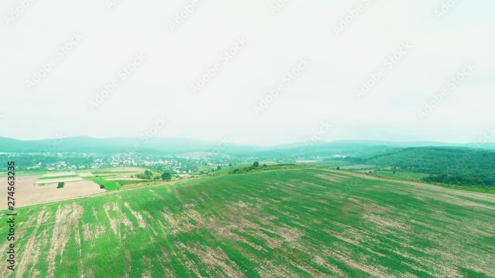 Little village is hiding under plouged, pure, green field. 4K. Little village is hiding under plouged, pure, green field. 4K.