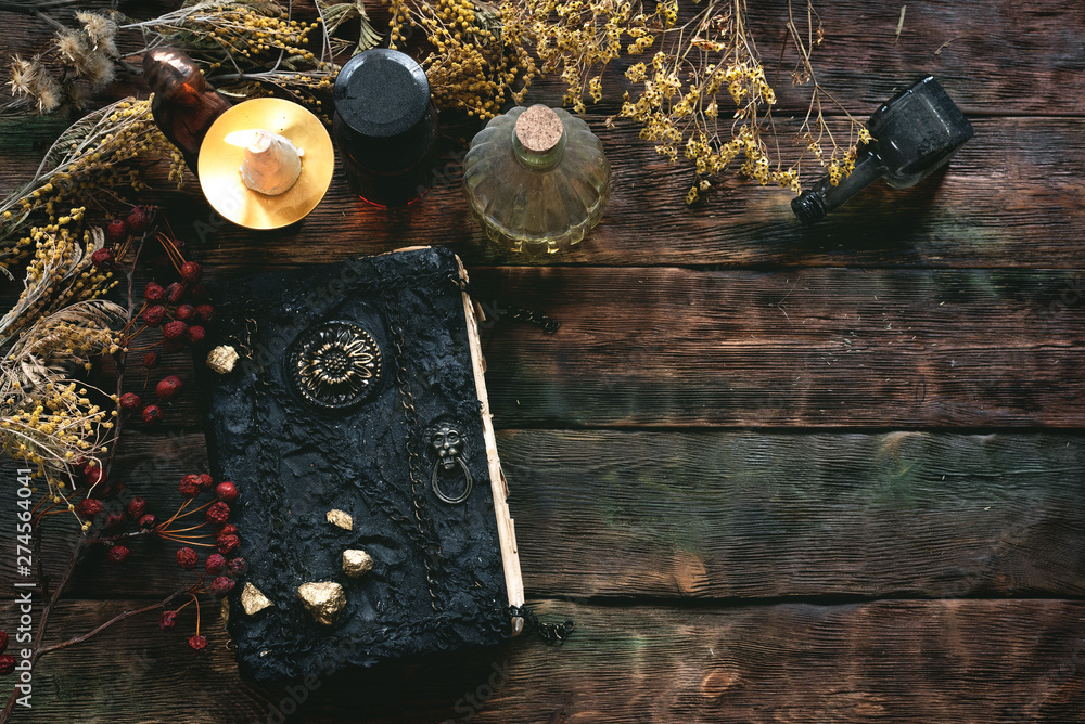Magic recipe book of witch doctor, dried herbs and a magic potion on a  wooden table. Witchcraft background. Druidism. Stock Photo
