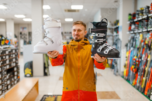 Man shows ski or snowboarding boots in sports shop photo