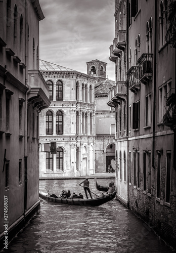 Venice in black and white, Italy. Old narrow street with lone gondola in distance. 