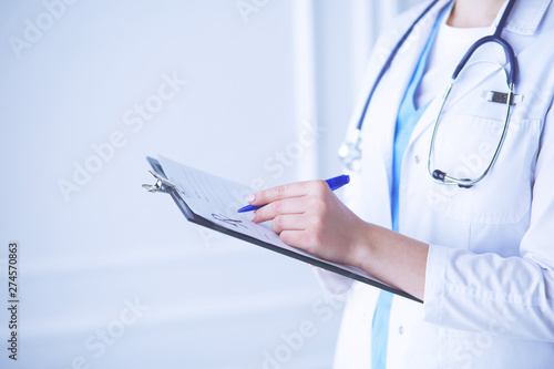 Young smiling female doctor with stethoscope holding a folder at a hospital's consulting room photo