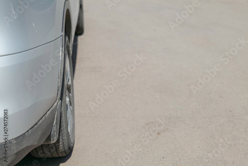 Wing of the car  color - metallic. Wheel  black rubber tire. Asphalt background -  deliberately blurred 