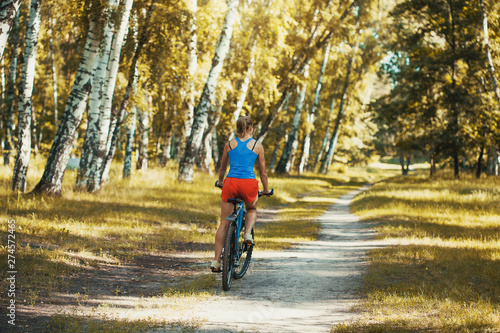cute blonde woman cyclist cycling mountain bike on the birch forest trail © Dmytro Titov