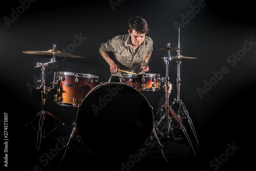 Professional drummer playing on drum set on stage on the black background Fototapet