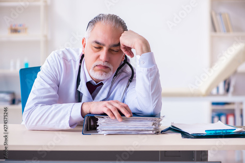 Old male doctor working in the clinic 