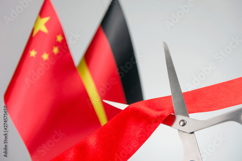 Ribbon cutting ceremony. Scissors cut red ribbon. .China and Germany flag bluered on the background. start of a partnership concept photo