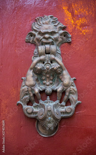 An old style decorative bronze door handle on a wooden red door, the distinctive feature and symbol of Malta in Mdina.