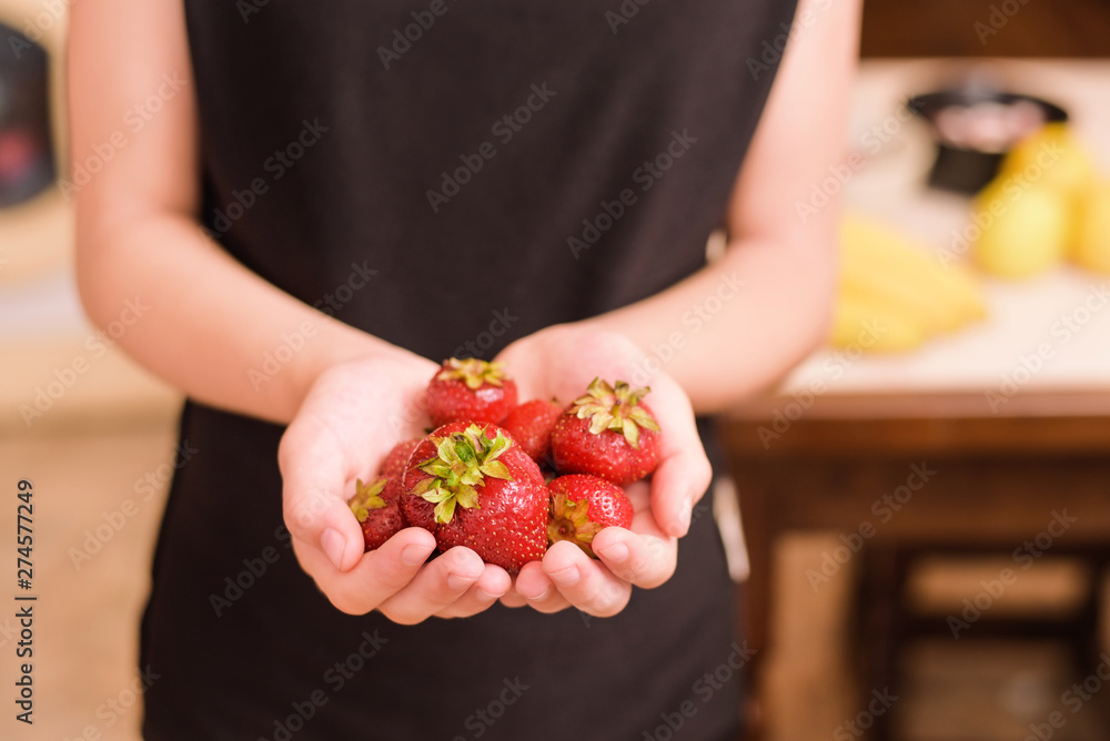 Young vegetarian girl holds a delicious, appetizing red strawberry in her hands Young vegetarian girl holds a delicious, appetizing red strawberry in her hands