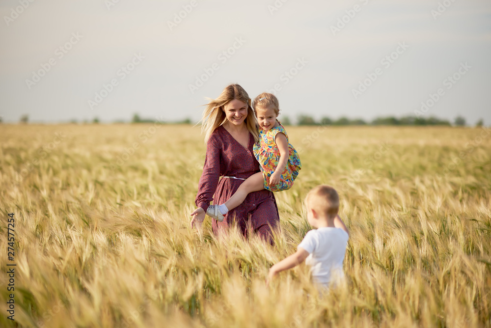 Family values. Happy mother and her children spending time together in sunny field. Mom hugging and loving her little kids. Care concept Family values. Happy mother and her children spending time together in sunny field. Mom hugging and loving her little kids. Care concept