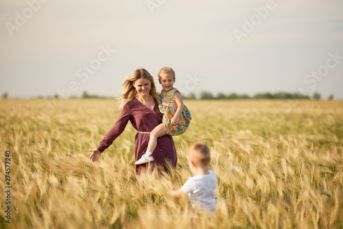 Family values. Happy mother and her children spending time together in sunny field. Mom hugging and loving her little kids. Care concept