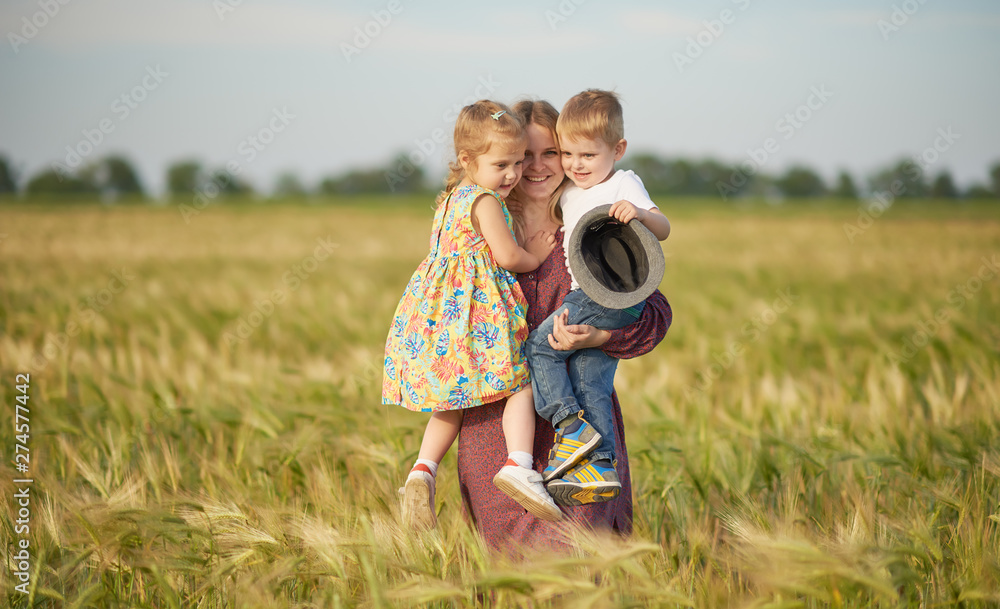 Family values. Happy mother and her children spending time together in sunny field. Mom hugging and loving her little kids. Care concept Family values. Happy mother and her children spending time together in sunny field. Mom hugging and loving her little kids. Care concept