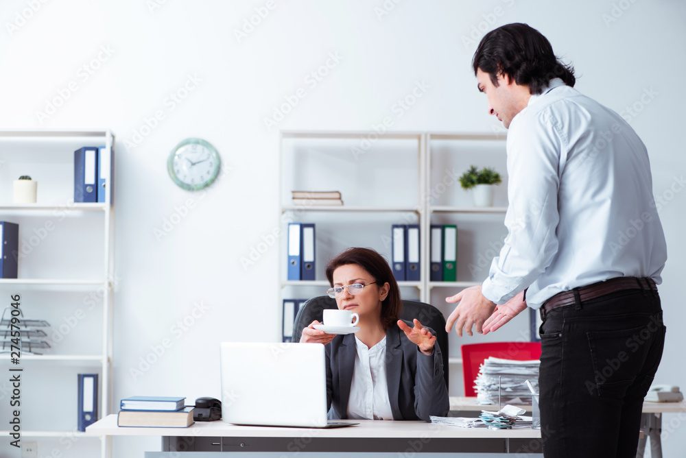 Old female boss and young male employee in the office  