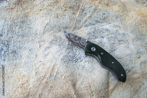 Damascus steel and green dymond wood handle go together to make a beautiful collectable or useable liner lock folding knife. Displayed on animal hide. Bokeh. photo