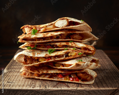 Mexican quesadilla stack with chicken, corn, black beans, cheese, vegetables on wooden board photo