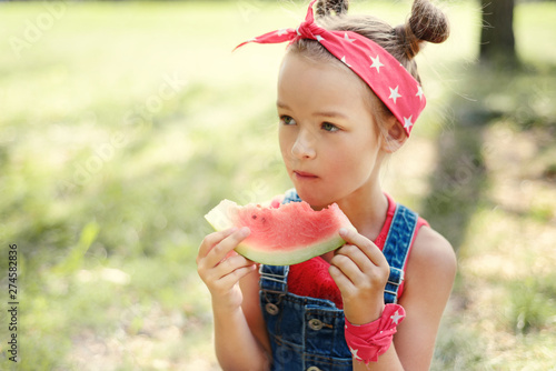 little girl eat watermelon. child in a red bandana with tails