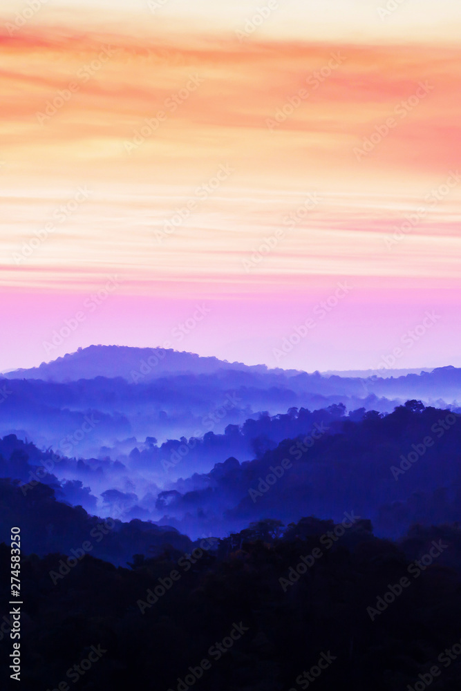 Dramatic clouds and sunrise sky over blue mountain.