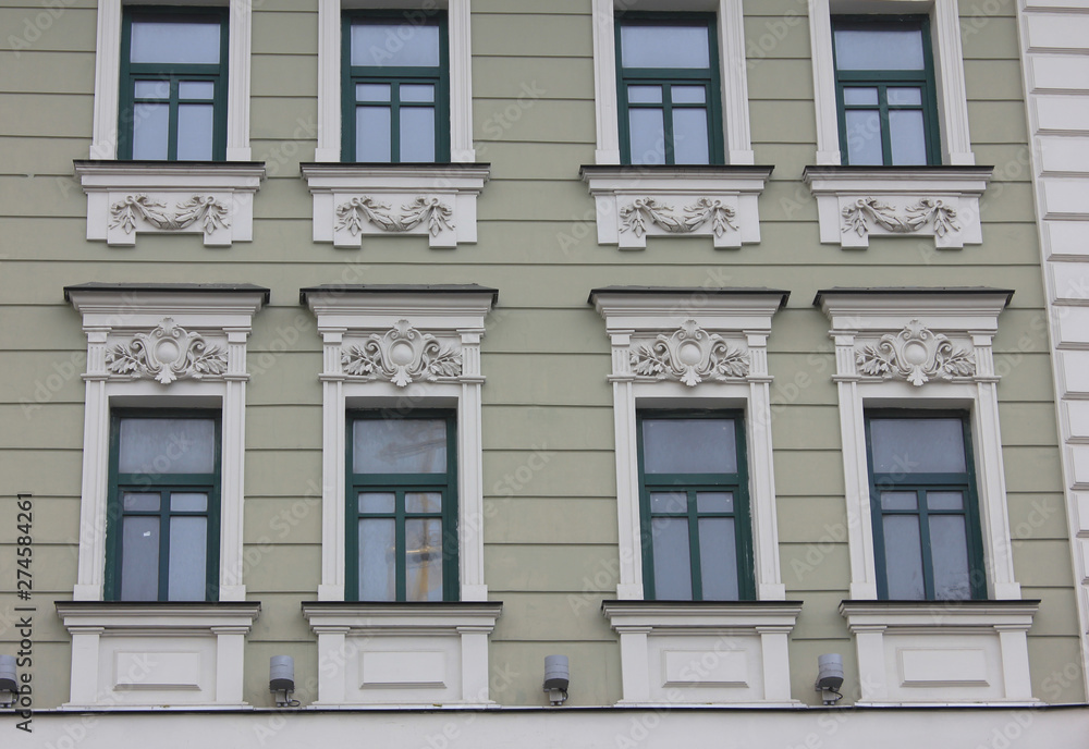 Old historical building facade of classic european house with windows in Moscow, Russia. Russian city typical architecture, close up view of building front facing the street Old historical building facade of classic european house with windows in Moscow, Russia. Russian city typical architecture, close up view of building front facing the street