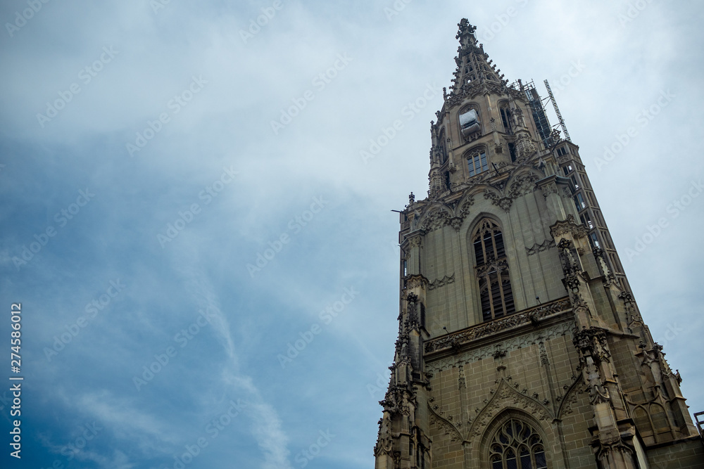 Low angle view of tower of Bern Munster on cloudy blue sky background with copy space Low angle view of tower of Bern Munster on cloudy blue sky background with copy space