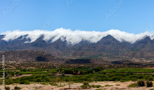 Panoramic view of the Cordillera of Bolivia. Clouds pour over mountain ranges and collapse into the valley