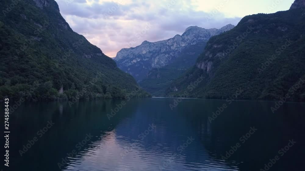 Slow aerial tracking shot of lake surrounded by mountains in the Dolomites, northern Italy at dusk Slow aerial tracking shot of lake surrounded by mountains in the Dolomites, northern Italy at dusk