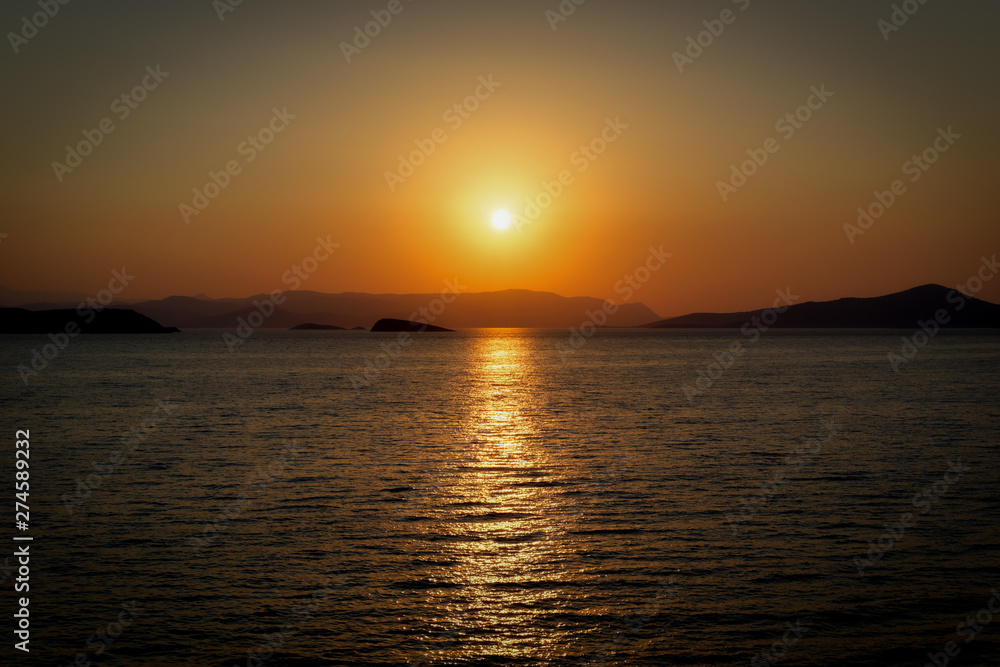 August summer sunset seascape with small islands in background, warm tones
