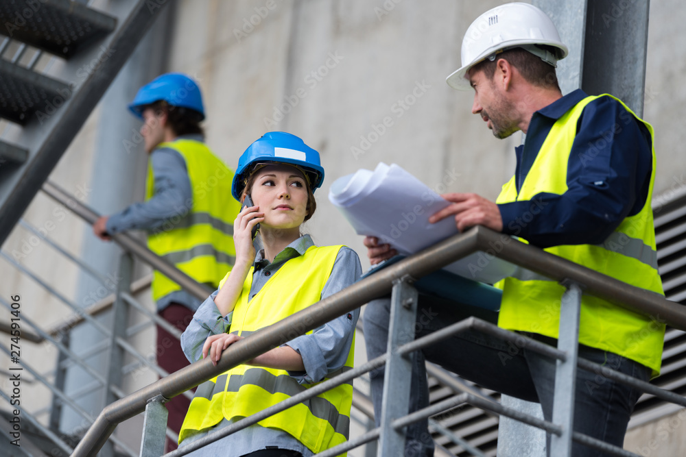 engineers on a staircase holding plans engineers on a staircase holding plans