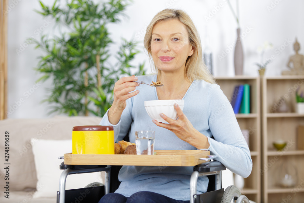 happy mature woman sitting in a wheelchair drinking coffee happy mature woman sitting in a wheelchair drinking coffee