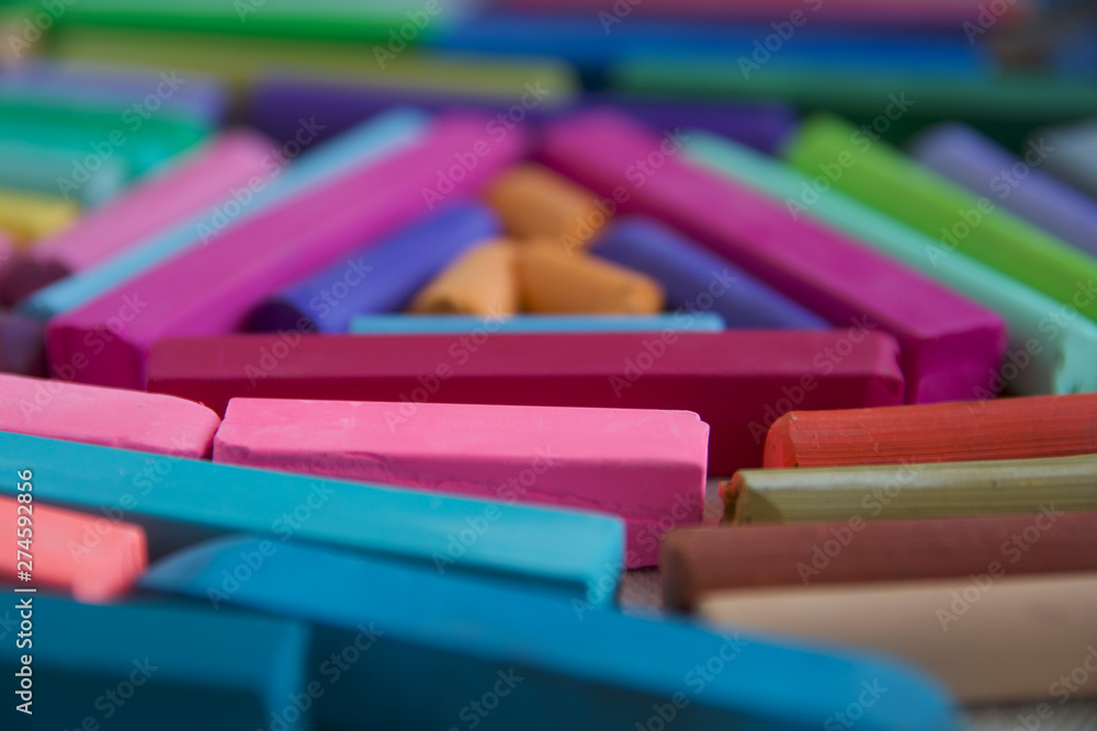 Blurred photo with chopsticks of multicolored art pastels suitable for the background. Symbol of creativity, joy, rich choice.