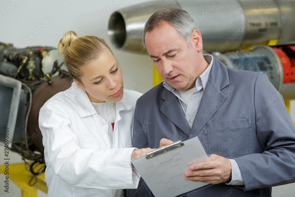 Obraz premium male and female aeronautical engineers conferring over clipboard