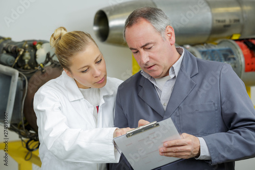 male and female aeronautical engineers conferring over clipboard