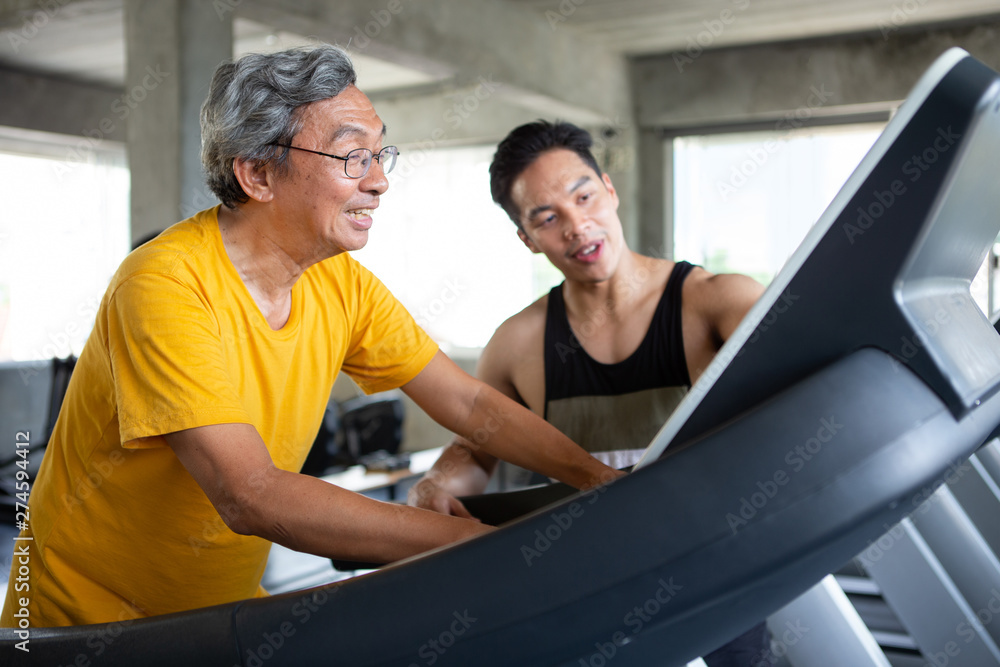 asian Senior man walking exercise on treadmill with Personal trainer workout in fitness gym . sport trainnig , retired , older , mature, elderly , smiling .rehab asian Senior man walking exercise on treadmill with Personal trainer workout in fitness gym . sport trainnig , retired , older , mature, elderly , smiling .rehab