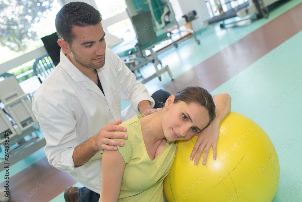 doctor examining pregnant woman on exercise ball