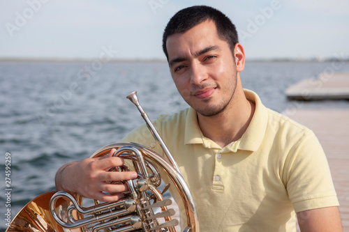 Portrait of teen musician playing instrument classic french horn.