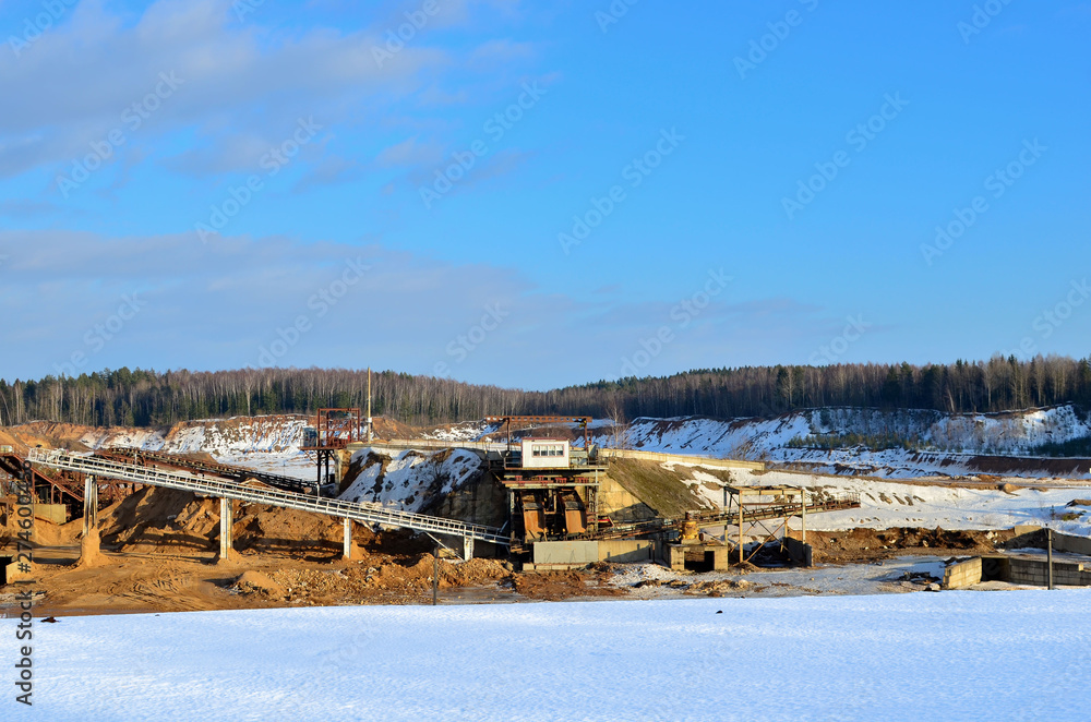 Sand mining in winter conditions in an industrial quarry. Conveyor Belt in mining quarry, Mining industry. Amazing mountains against the backdrop of snow and industry