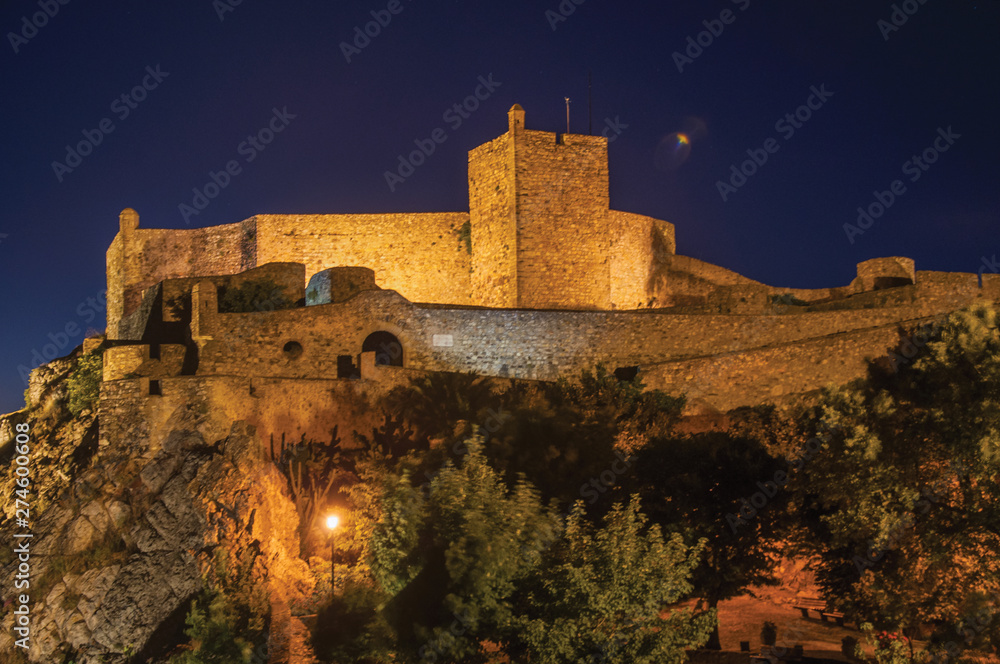 Walls and tower of Castle over rocky cliff at dusk in Marvao