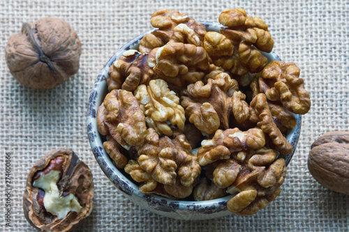 Whole walnuts and walnut kernels in a small bowl. Flat lay