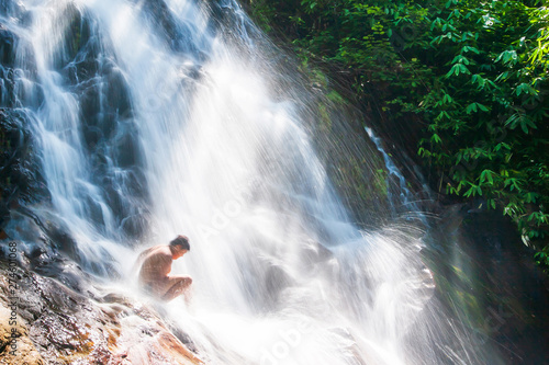 Happy Asian boy playing in freshwater of tropical waterfall. photo