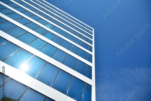 New office building in business center. Wall made of steel and glass with blue sky. 