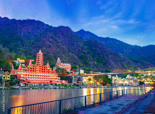   River Ganges, the famous bridge Laxman Jhula  surrounded by temples and mountains around in rishikesh, India 