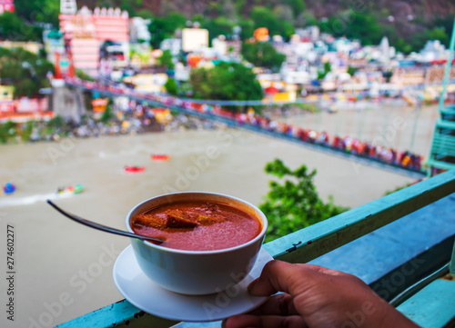 delicious Tomato soup at the edge of the wall with a blurred bridge background and rafting in Rishikesh, India photo