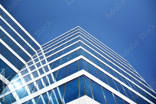 New office building in business center. Wall made of steel and glass with blue sky. 
