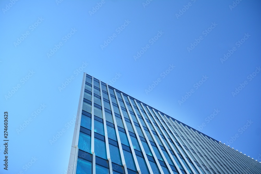 New office building in business center. Wall made of steel and glass with blue sky. 